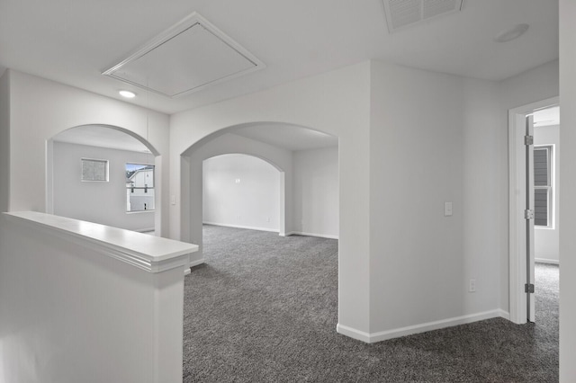 hallway featuring attic access, visible vents, dark carpet, and baseboards