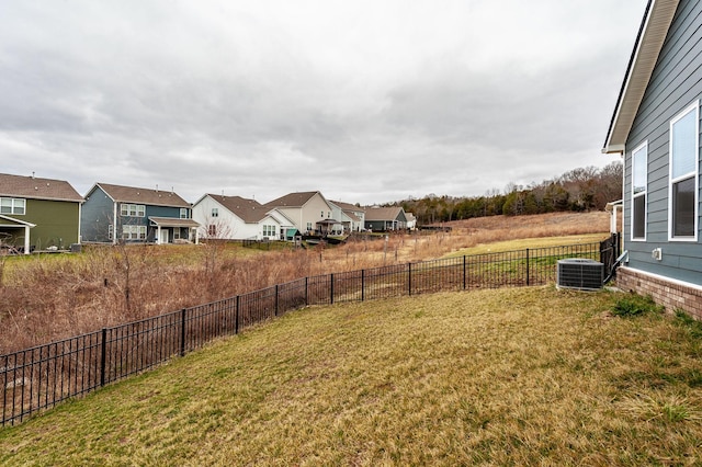 view of yard with a residential view, central AC unit, and fence