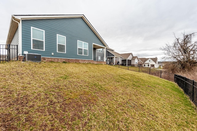 rear view of house featuring cooling unit, fence, and a yard