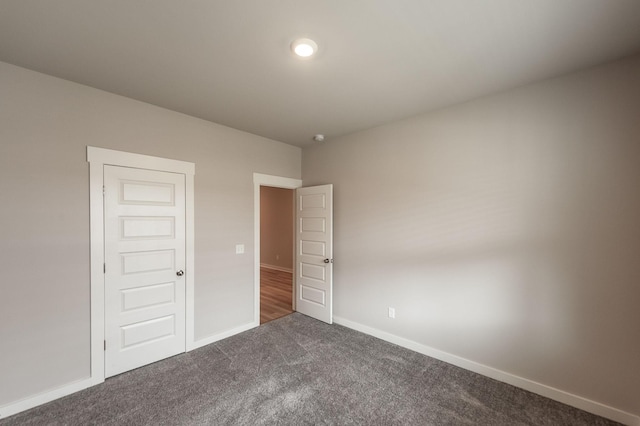 unfurnished bedroom with baseboards and dark colored carpet