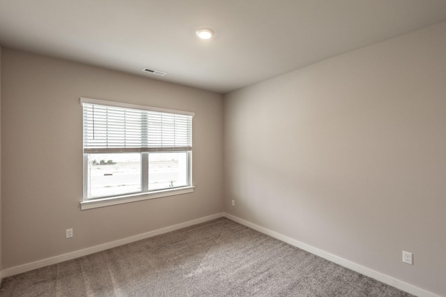 spare room with visible vents, carpet, and baseboards