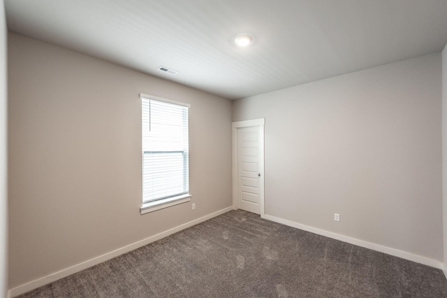 empty room with visible vents, baseboards, and dark carpet