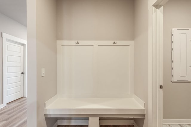 mudroom with electric panel, baseboards, and wood finished floors