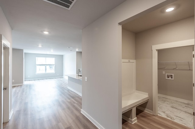 mudroom with wood finished floors, baseboards, visible vents, and a sink