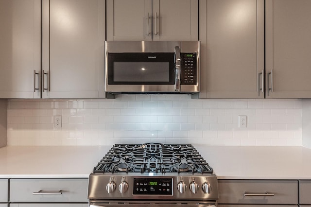 kitchen featuring stainless steel appliances, backsplash, gray cabinets, and light countertops