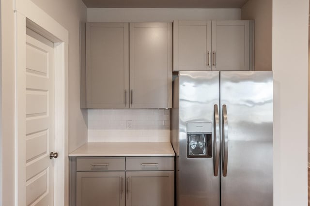 kitchen featuring tasteful backsplash, gray cabinetry, light countertops, and stainless steel fridge with ice dispenser