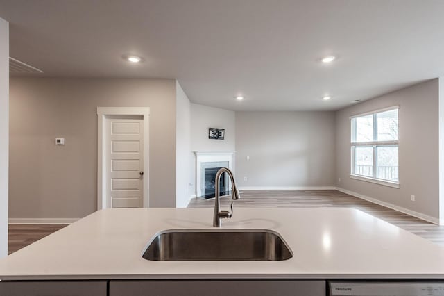 kitchen with a kitchen island with sink, a sink, light countertops, dishwasher, and open floor plan