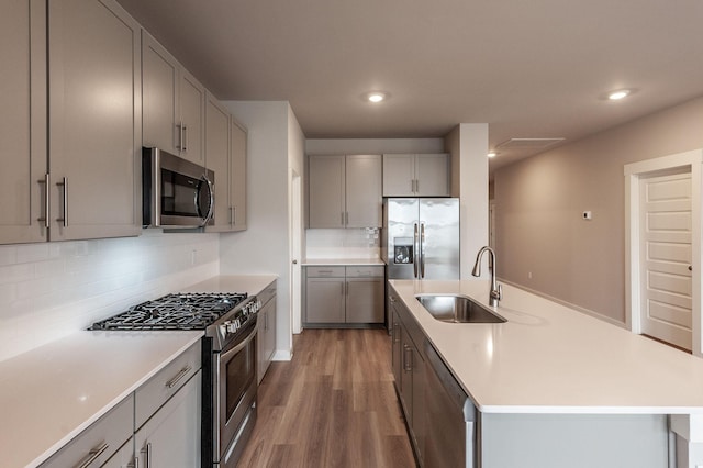 kitchen with gray cabinetry, light countertops, wood finished floors, stainless steel appliances, and a sink