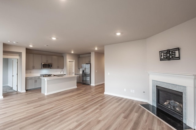 kitchen with open floor plan, gray cabinetry, stainless steel appliances, and an island with sink