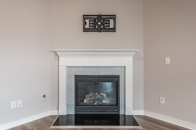 interior details with a fireplace with flush hearth, baseboards, and wood finished floors