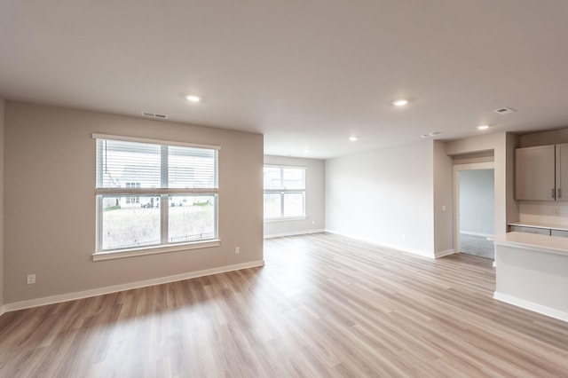 unfurnished living room featuring visible vents, recessed lighting, light wood-type flooring, and baseboards