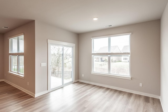 spare room featuring visible vents, light wood-type flooring, and baseboards