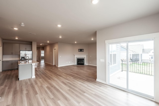 unfurnished living room with light wood-style flooring, plenty of natural light, a fireplace, and recessed lighting