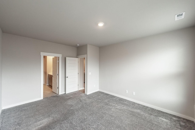 unfurnished bedroom featuring visible vents, carpet floors, baseboards, and ensuite bathroom