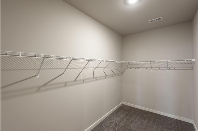 walk in closet featuring visible vents and dark colored carpet