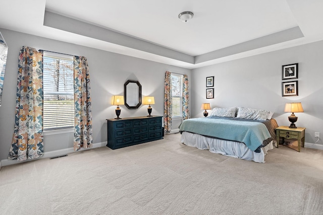 carpeted bedroom with a raised ceiling, visible vents, and baseboards