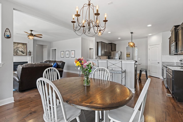 dining space featuring baseboards, dark wood-style floors, ceiling fan, a fireplace, and recessed lighting