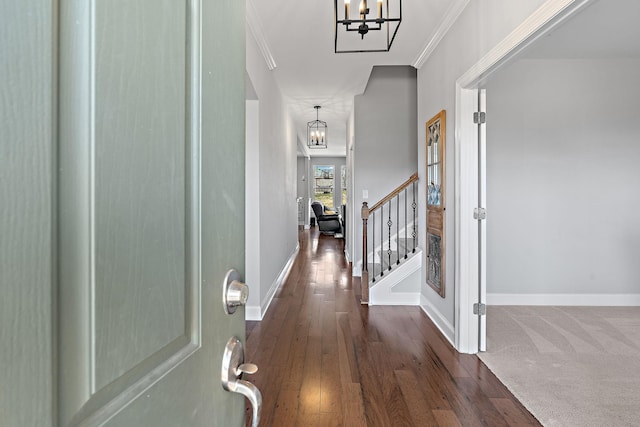 hall with stairway, ornamental molding, wood finished floors, a chandelier, and baseboards