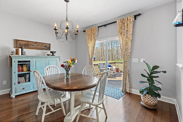 dining space with dark wood-style flooring, a notable chandelier, and baseboards