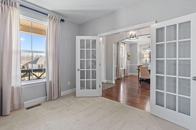 carpeted spare room with french doors, visible vents, a notable chandelier, and baseboards