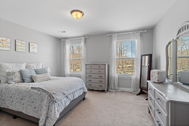 bedroom with baseboards, visible vents, and light colored carpet