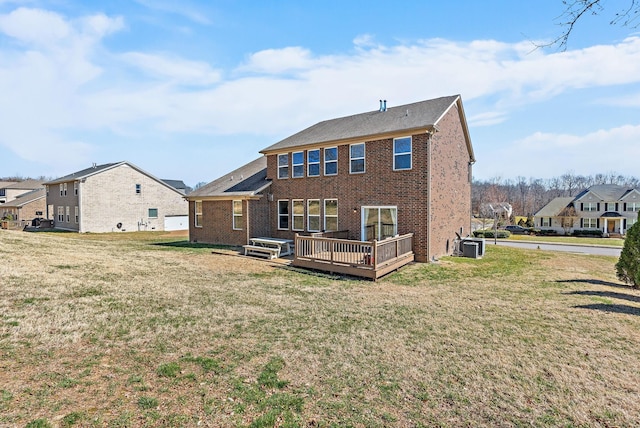 rear view of property with brick siding, a lawn, cooling unit, and a wooden deck