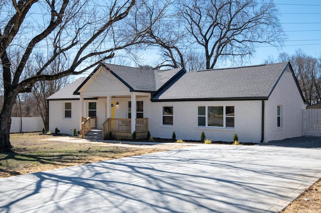 view of front of home with covered porch, a shingled roof, fence, and brick siding