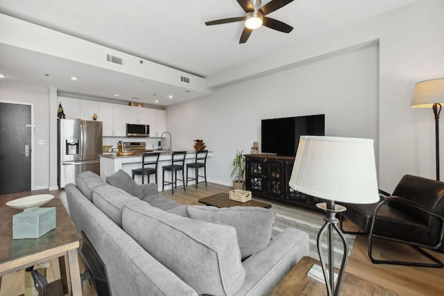 living room featuring light wood-style flooring, visible vents, ceiling fan, and recessed lighting