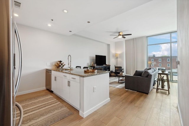 kitchen featuring a peninsula, a sink, open floor plan, appliances with stainless steel finishes, and a wall of windows