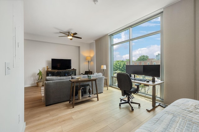 home office featuring light wood finished floors, expansive windows, baseboards, and a ceiling fan