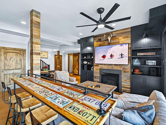 living area with built in shelves, recessed lighting, a fireplace, and ceiling fan