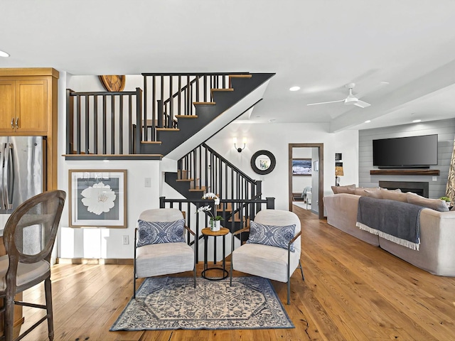 interior space with ceiling fan, recessed lighting, a fireplace, stairway, and light wood finished floors