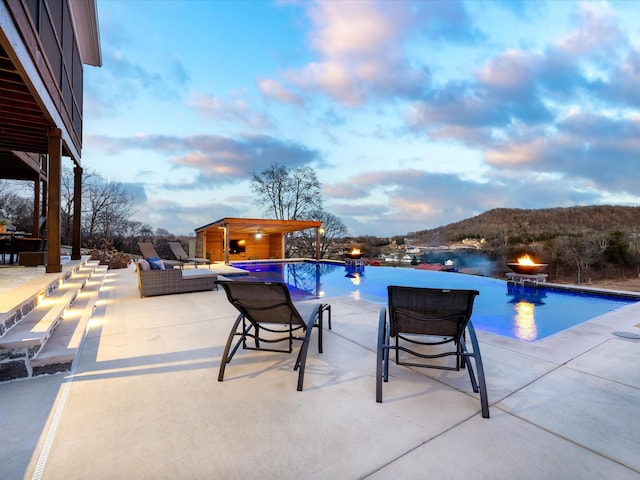 pool at dusk featuring a patio, an outdoor living space, and an outdoor pool