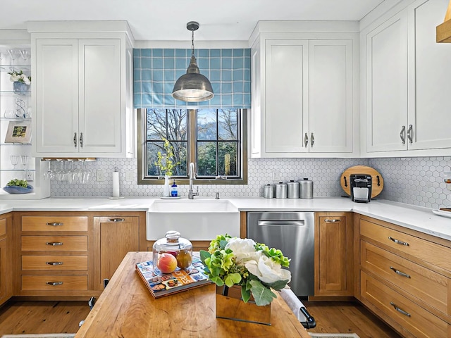 kitchen with white cabinets, a sink, hanging light fixtures, and stainless steel dishwasher