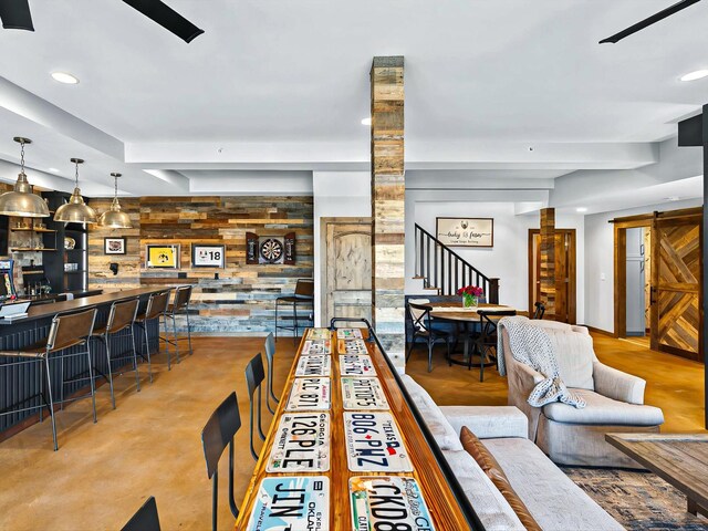 living room with wood walls, a barn door, stairway, and recessed lighting