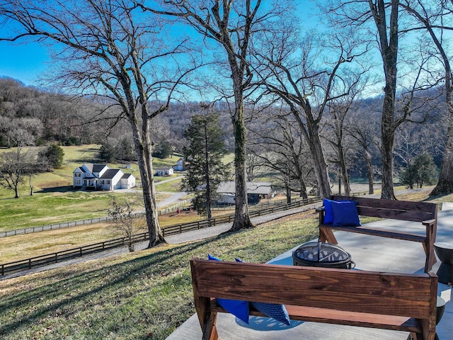 view of yard with an outdoor fire pit, a patio area, fence, and a forest view