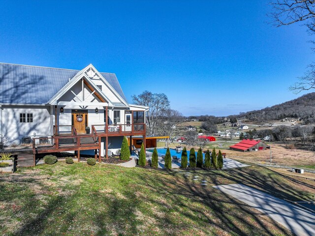 back of house featuring metal roof, a lawn, and a wooden deck