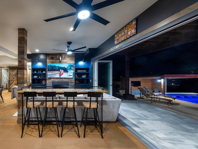 home theater featuring ornate columns, a barn door, a fireplace, and a ceiling fan