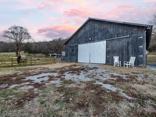 view of outdoor structure with fence and an outbuilding