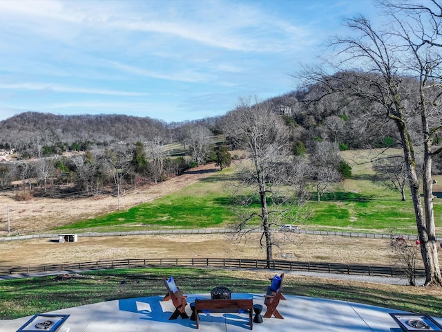 surrounding community featuring an outdoor fire pit, fence, and a rural view