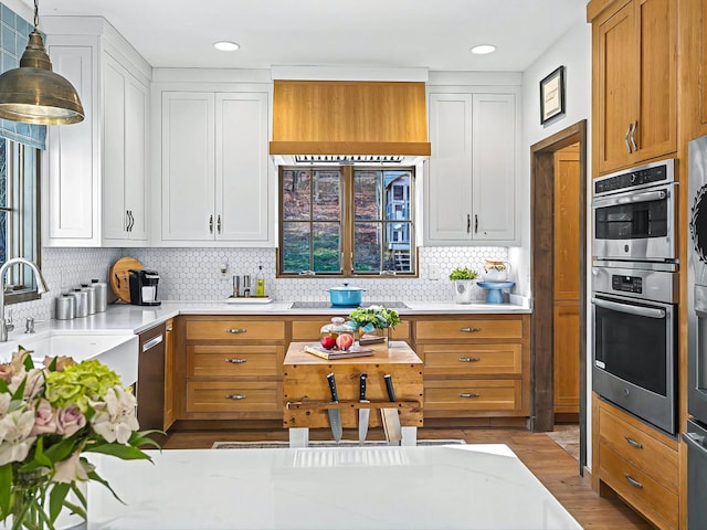 kitchen featuring pendant lighting, stainless steel appliances, white cabinets, and decorative backsplash