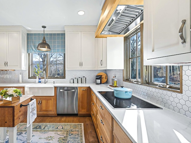 kitchen featuring a wealth of natural light, wall chimney range hood, stainless steel dishwasher, and black electric cooktop