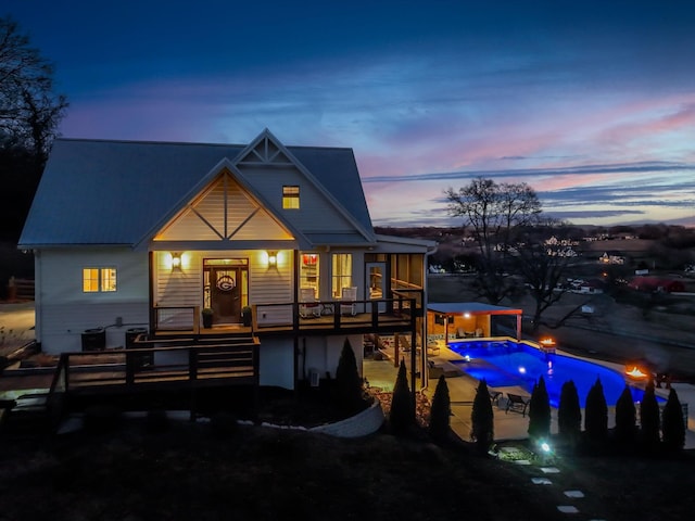 back of property featuring a deck, a patio, and an outdoor pool