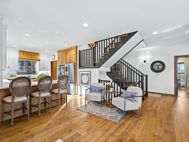 living area with baseboards, stairway, light wood-style flooring, and recessed lighting