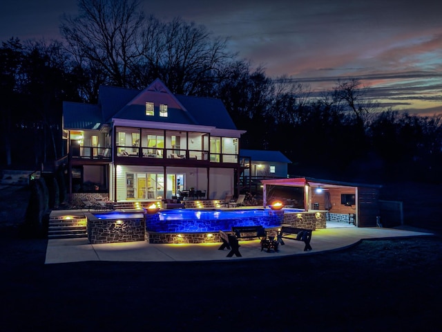 back of property with a pool with connected hot tub, a patio area, and a balcony