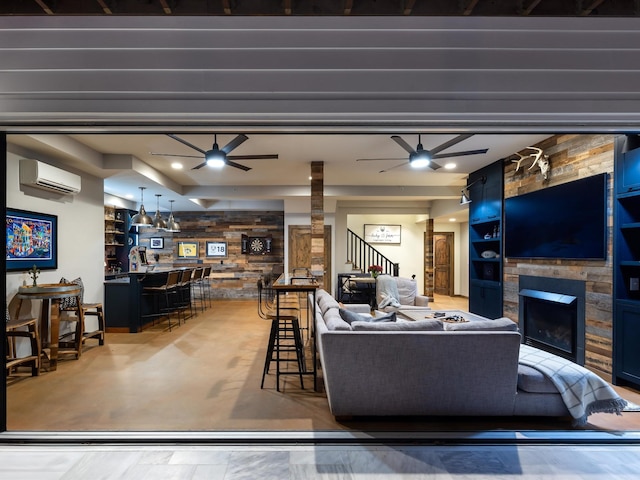 living area with built in shelves, stairs, a ceiling fan, and a stone fireplace