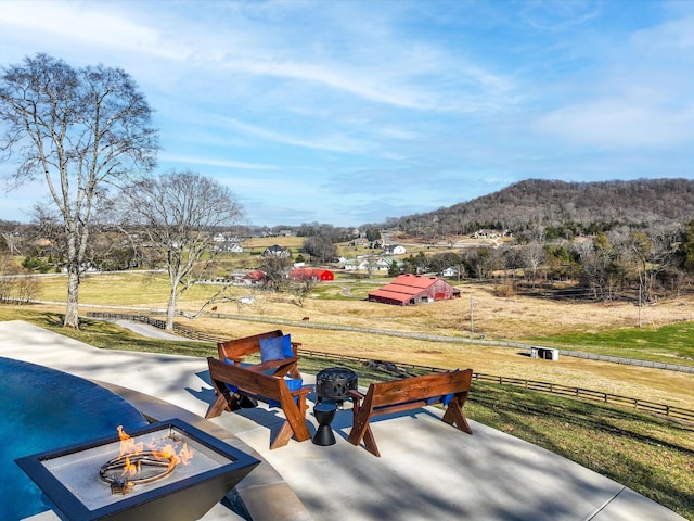 view of community with a mountain view, fence, a fire pit, and a patio