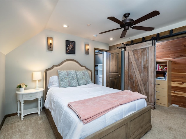 bedroom with ceiling fan, lofted ceiling, a barn door, recessed lighting, and light carpet