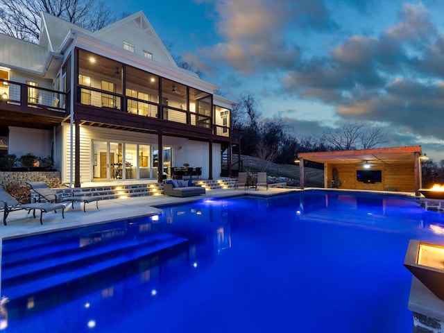 pool at dusk featuring a ceiling fan, a fenced in pool, a patio area, and outdoor lounge area