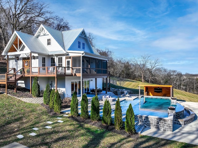 back of house featuring metal roof, a patio, a sunroom, stairs, and a standing seam roof